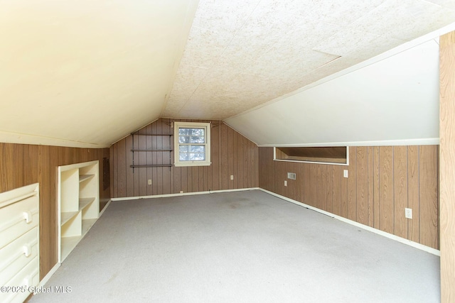 additional living space featuring lofted ceiling, carpet flooring, and wood walls