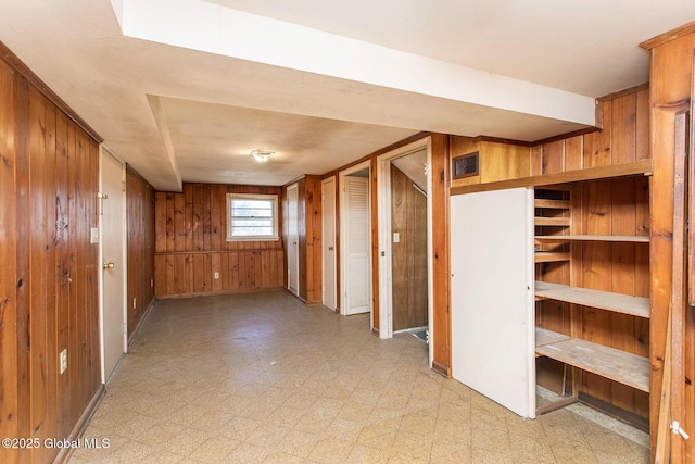 basement with light floors, visible vents, and wood walls