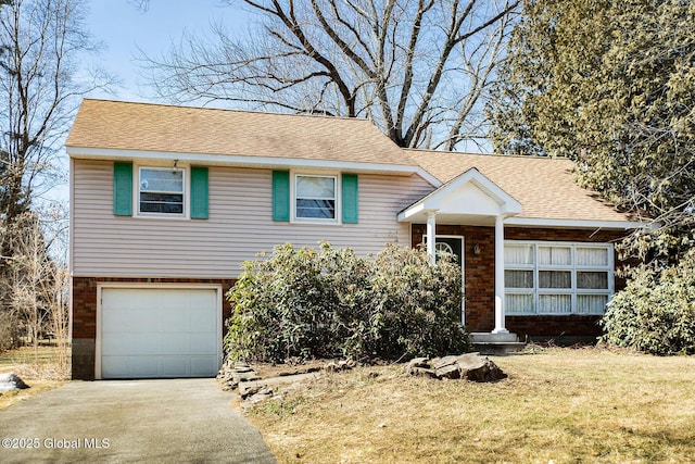 split level home featuring aphalt driveway, an attached garage, brick siding, and roof with shingles