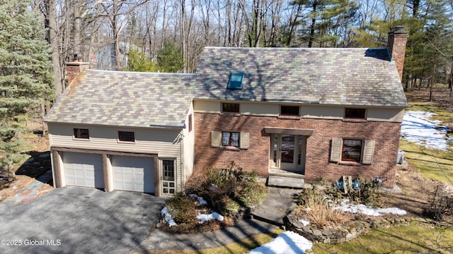 view of front of property with aphalt driveway, brick siding, and a chimney