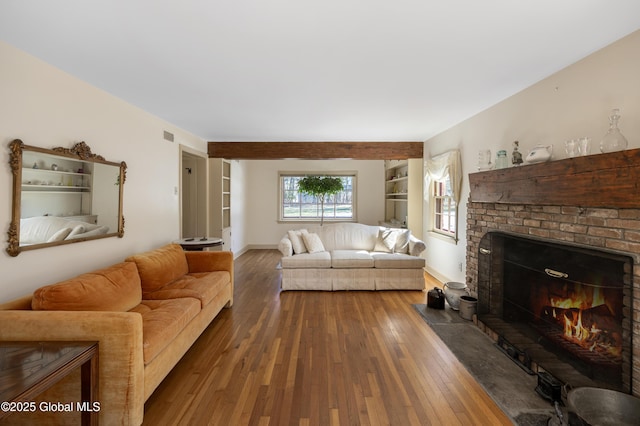 living area featuring built in features, baseboards, wood-type flooring, and a fireplace