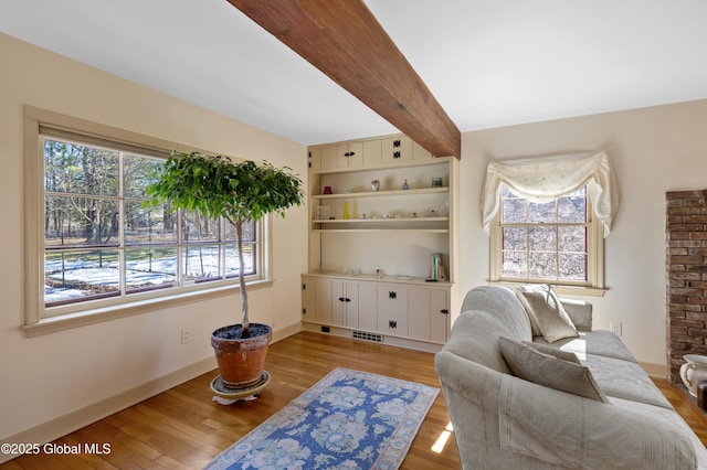 sitting room with beamed ceiling, light wood-style flooring, visible vents, and baseboards