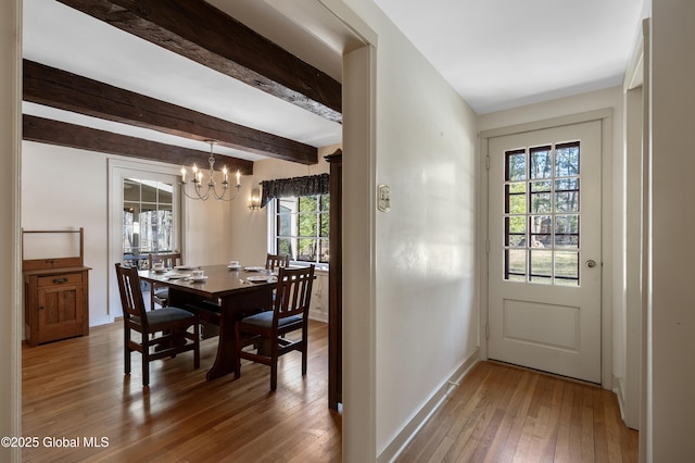 dining space featuring beamed ceiling, baseboards, hardwood / wood-style floors, and a chandelier