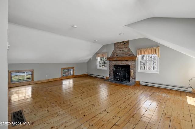 additional living space featuring a baseboard heating unit, lofted ceiling, visible vents, and hardwood / wood-style flooring