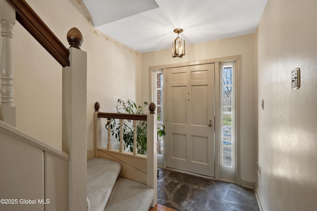 foyer entrance with stairway and baseboards