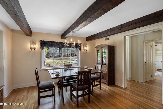 dining area featuring visible vents, beam ceiling, wood finished floors, an inviting chandelier, and baseboards