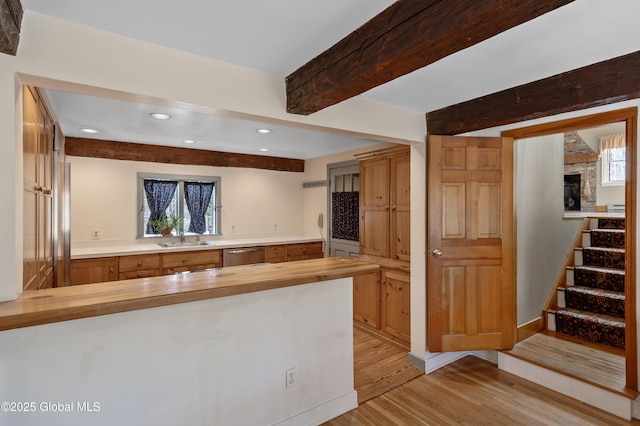 kitchen featuring wooden counters, dishwasher, beam ceiling, light wood-style flooring, and a peninsula