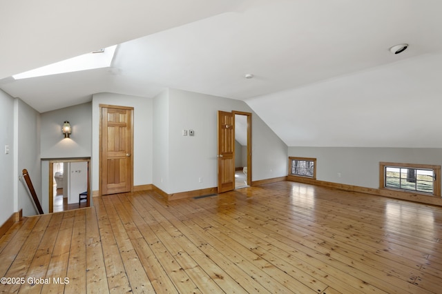 bonus room featuring lofted ceiling with skylight, baseboards, light wood-type flooring, and visible vents