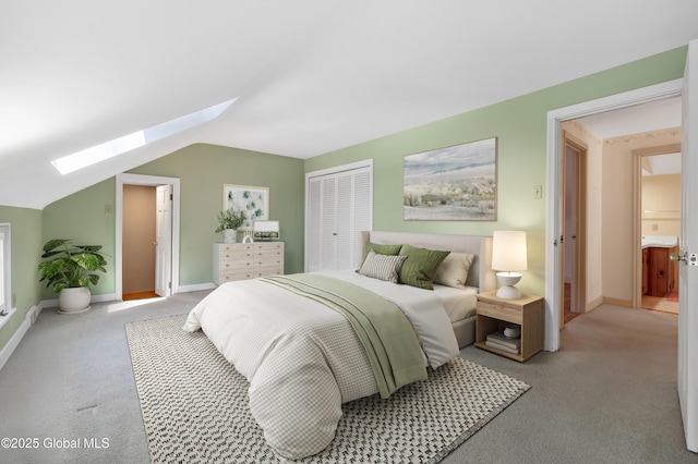 bedroom featuring baseboards, vaulted ceiling with skylight, light carpet, and a closet