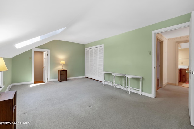 additional living space featuring lofted ceiling with skylight, baseboards, and carpet