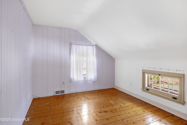 additional living space featuring a wealth of natural light, visible vents, lofted ceiling, and wood-type flooring