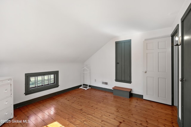 bonus room with visible vents, baseboards, light wood-style flooring, and vaulted ceiling