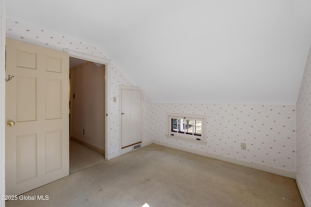 additional living space with visible vents, baseboards, vaulted ceiling, and wallpapered walls