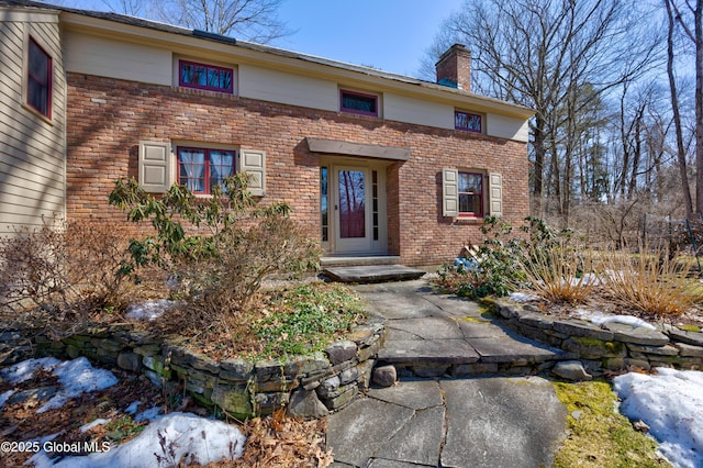 entrance to property featuring brick siding and a chimney