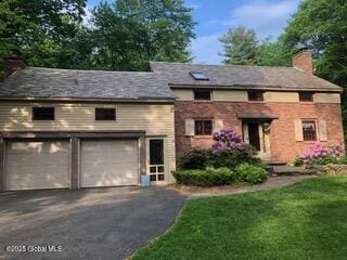 view of front of house with a front lawn, a garage, driveway, and a chimney