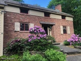 view of front of house featuring brick siding and a chimney