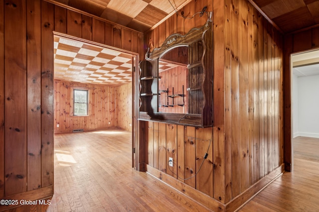 corridor with wood ceiling, wood walls, and hardwood / wood-style flooring