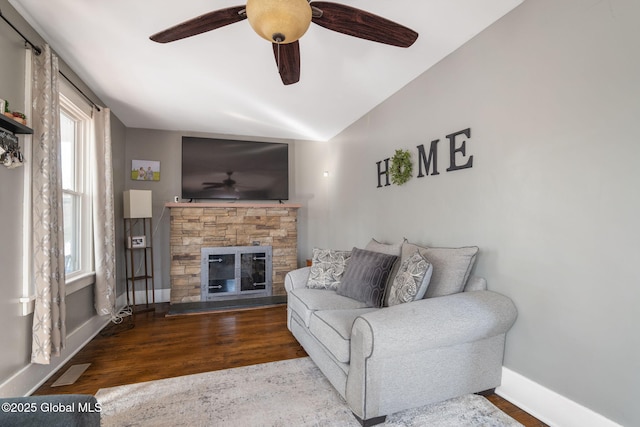 living area with visible vents, baseboards, ceiling fan, a fireplace, and wood finished floors