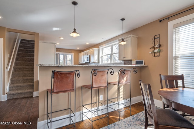 dining area featuring stairs, plenty of natural light, dark wood-style floors, and baseboards