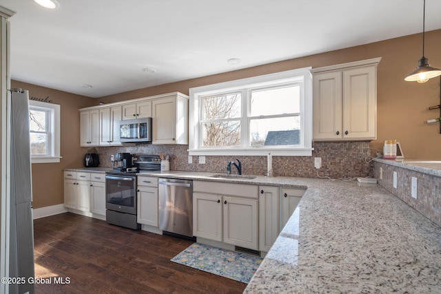 kitchen with a sink, light stone counters, tasteful backsplash, dark wood-style floors, and stainless steel appliances