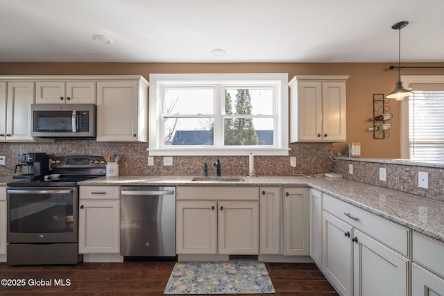 kitchen featuring backsplash, wood tiled floor, decorative light fixtures, appliances with stainless steel finishes, and a sink