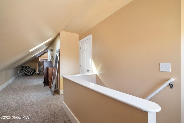 hallway featuring carpet, lofted ceiling, an upstairs landing, and baseboards