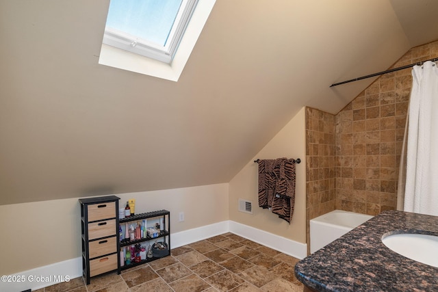 full bathroom with lofted ceiling with skylight, visible vents, baseboards, and a sink