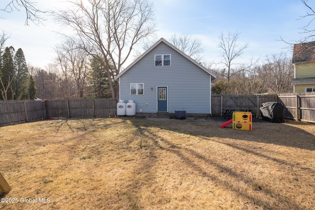 rear view of house featuring a yard and a fenced backyard