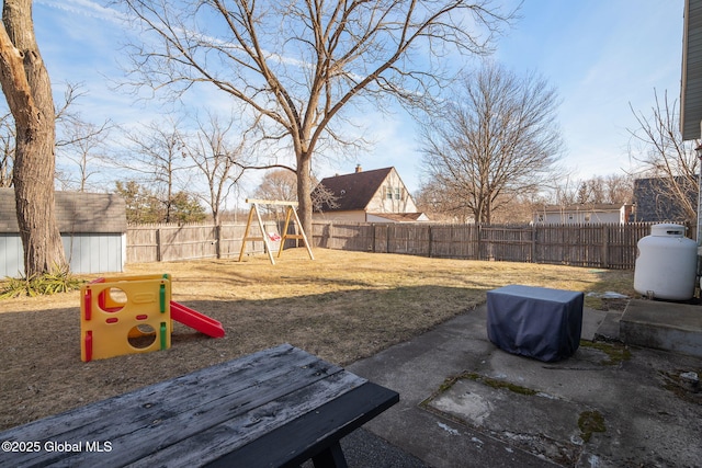 view of yard featuring a storage shed, an outdoor structure, a playground, and a fenced backyard