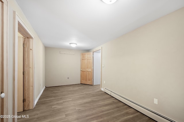 unfurnished bedroom with a baseboard heating unit, light wood-style flooring, and baseboards
