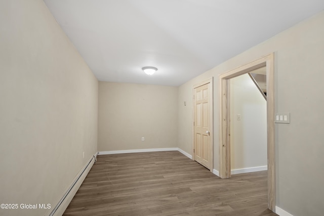 unfurnished room featuring wood finished floors, baseboards, and baseboard heating