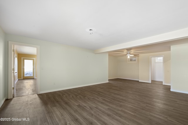 unfurnished room with a ceiling fan, baseboards, and dark wood-style flooring