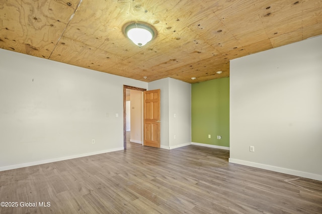 empty room with wood finished floors, wood ceiling, and baseboards