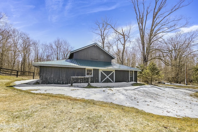 view of side of home featuring metal roof, an outbuilding, a barn, and fence