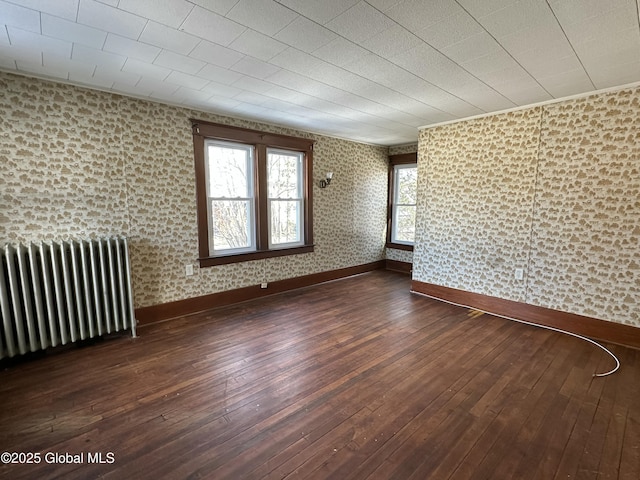 unfurnished room with baseboards, radiator, and hardwood / wood-style floors