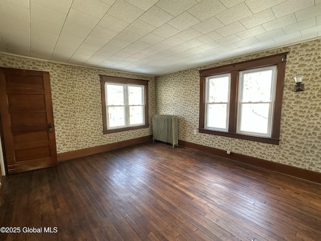 empty room with baseboards, radiator, dark wood-style floors, and wallpapered walls