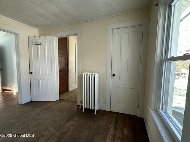 unfurnished bedroom with radiator and dark wood-type flooring