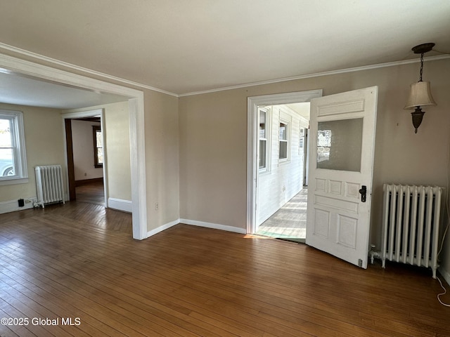 spare room featuring dark wood finished floors, radiator, and crown molding