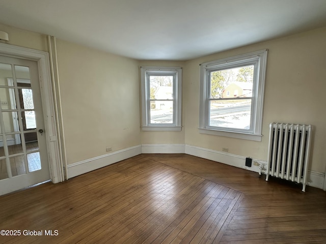 empty room with hardwood / wood-style flooring, radiator heating unit, and baseboards