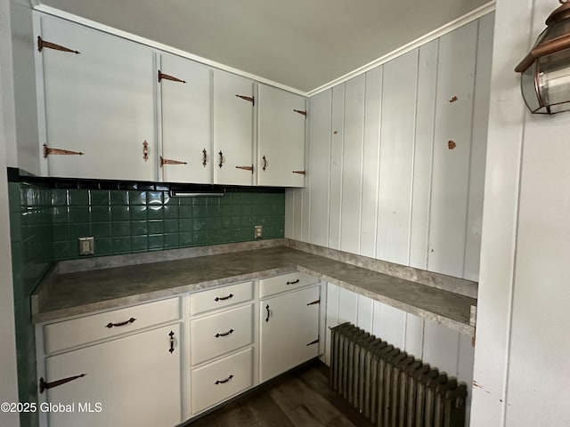 kitchen with decorative backsplash, white cabinets, radiator, and dark wood-style flooring