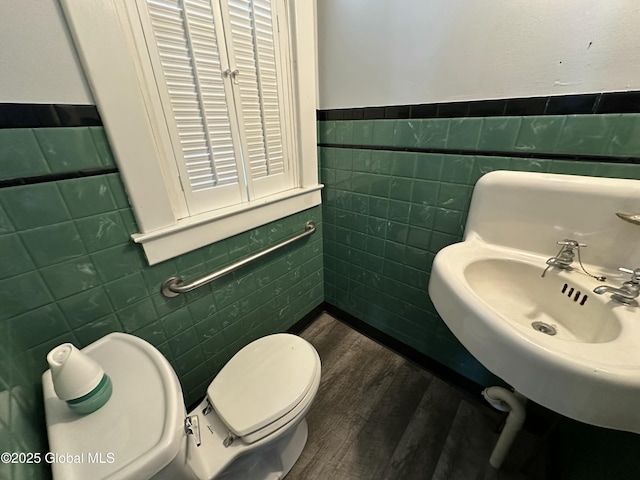 bathroom featuring tile walls, toilet, and wood finished floors