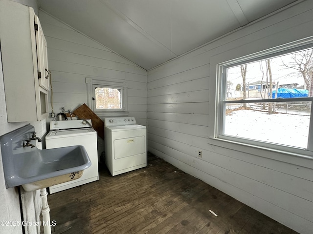 laundry area featuring a sink, dark wood finished floors, cabinet space, wooden walls, and washing machine and clothes dryer