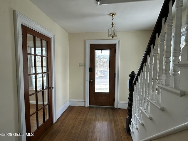 foyer entrance with plenty of natural light, baseboards, stairs, and dark wood-type flooring