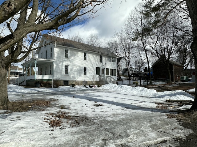 view of snow covered exterior featuring a porch and roof with shingles