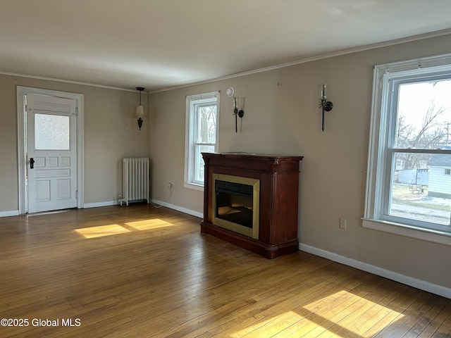 unfurnished living room with baseboards, light wood-style flooring, radiator heating unit, and ornamental molding