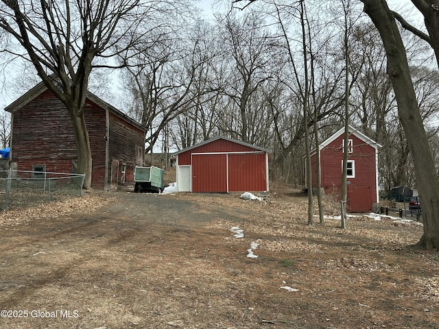 view of yard featuring a garage, an outbuilding, and dirt driveway