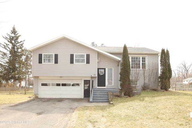 split foyer home featuring aphalt driveway, a front lawn, an attached garage, and fence