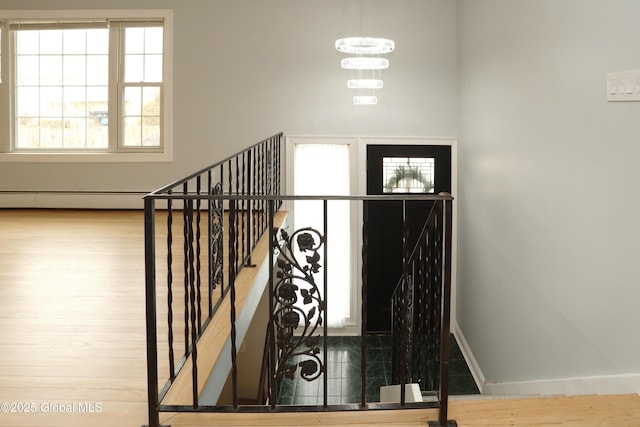 stairway with baseboards, an inviting chandelier, and wood finished floors