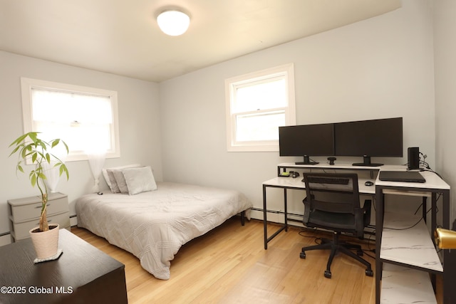 bedroom featuring a baseboard heating unit, multiple windows, baseboard heating, and light wood finished floors