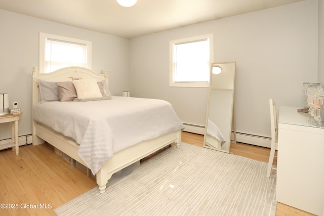 bedroom featuring multiple windows, light wood-style floors, and a baseboard radiator